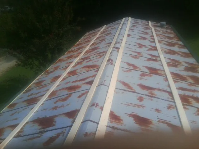 Rusted metal roof panels with new wood purlins before replacement — Storm Damage Roof Repair in Gilcrest by Roofing Brothers