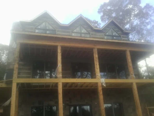 Dormers and porch framing on a large log home under construction — Roof Coating work by our crew in Gilcrest
