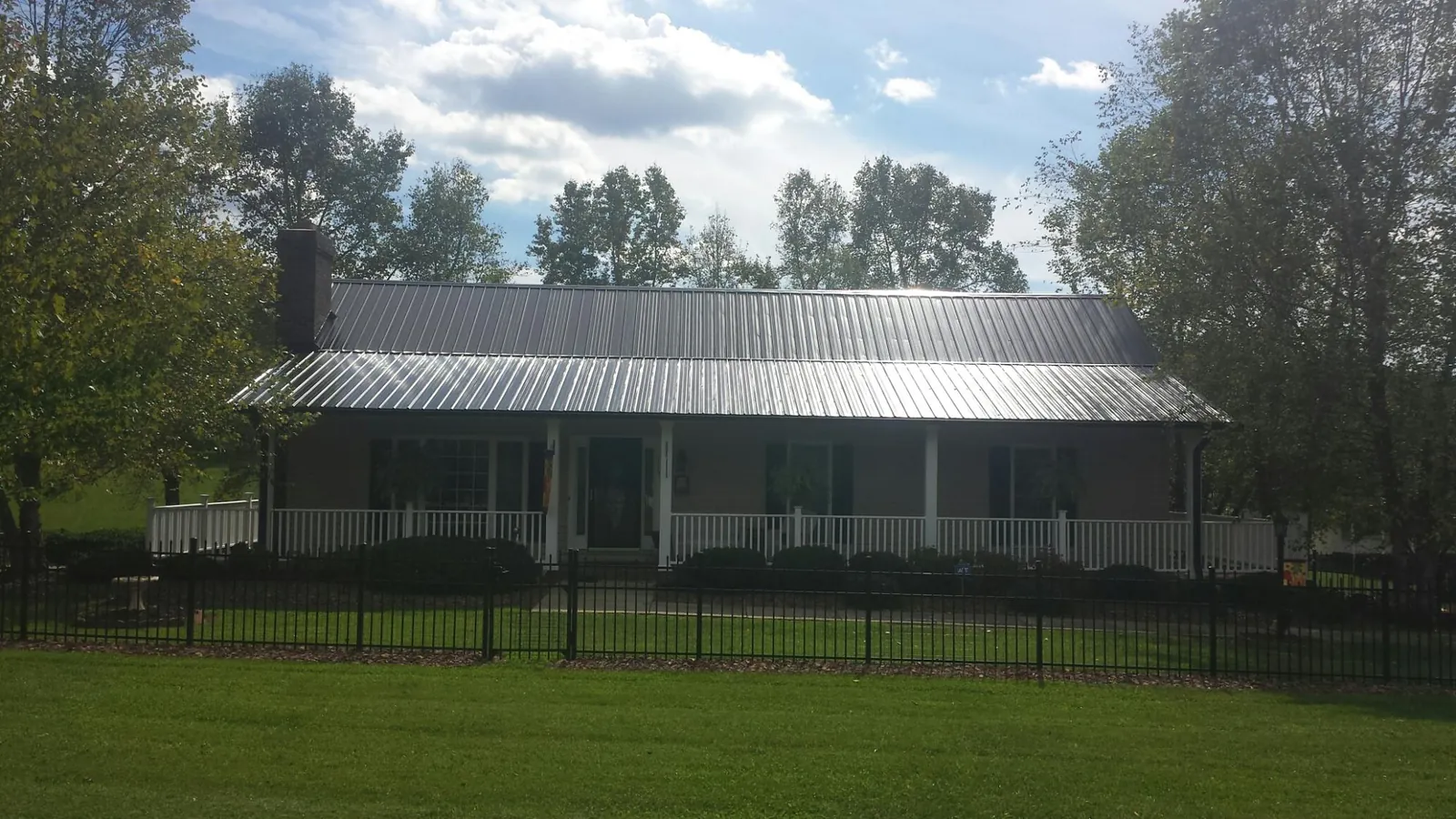 Gray metal roof on a brick ranch with a full width front porch — Gutter Guard Installation work by our crew in Gilcrest
