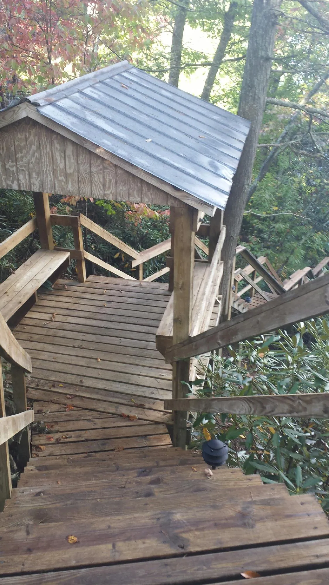 Metal roofed shelter over wooden steps on a wooded walkway — Skylight Repair & Installation work by our crew in Gilcrest