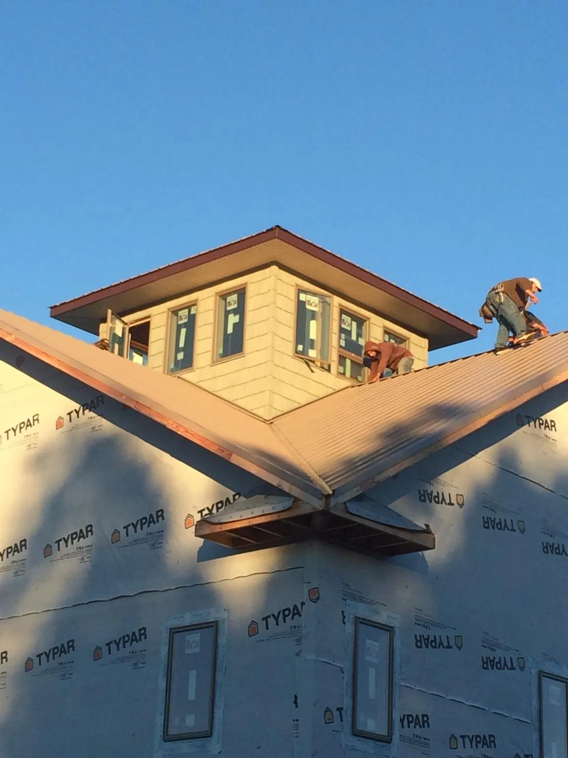 Roofers working around a rooftop cupola on a new metal roof at sunset — Roof Waterproofing in Gilcrest by Roofing Brothers